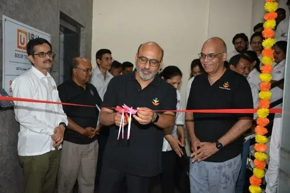 Bagwe Sir cutting the ribbon at the entrance of the new Urja-Disha office, beside the company signboard and marigold garlands