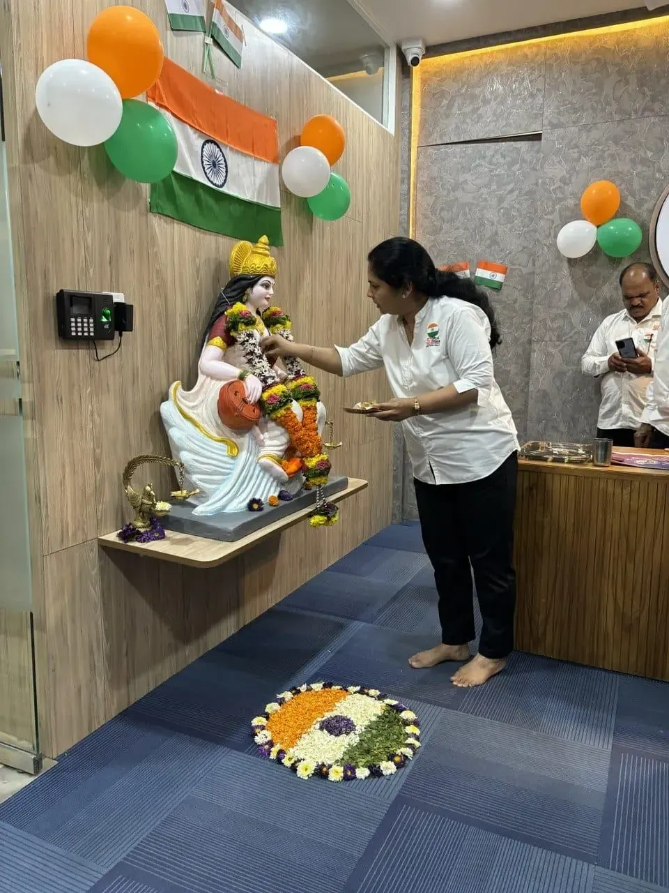A colleague offering flowers at the garlanded Saraswati idol, decorated with tricolour balloons and the national flag for Republic Day