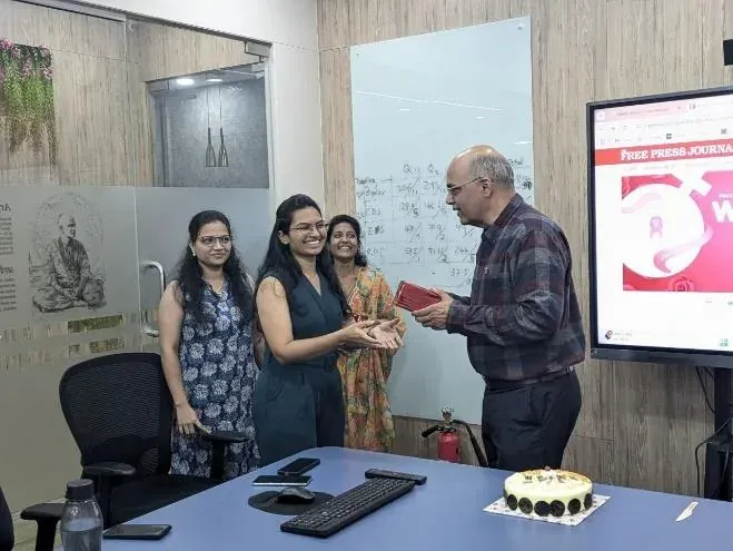 A woman engineer receiving her Women's Day gift from a senior colleague in the conference room