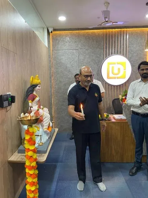 Bagwe Sir lighting a lamp before the garlanded Saraswati idol in the new office reception