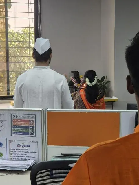 A colleague in a white Gandhi cap garlanding the idol of Chhatrapati Shivaji Maharaj set up beside the workstations
