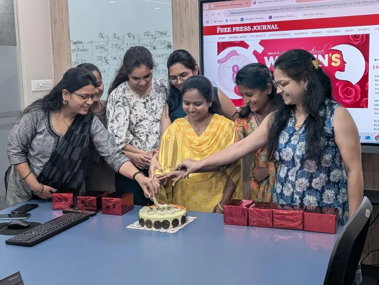 The women of Urja-Disha cutting the Women's Day cake together in the conference room