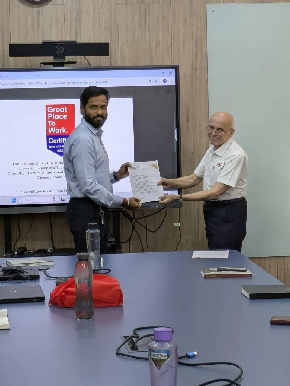 A colleague receiving his appreciation letter with the Great Place To Work Certified badge displayed on the screen behind