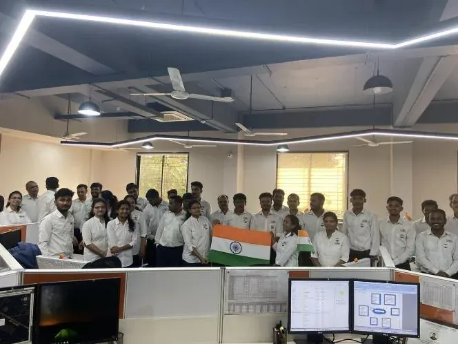 Design office team holding the national flag together on Republic Day, standing among the engineering workstations