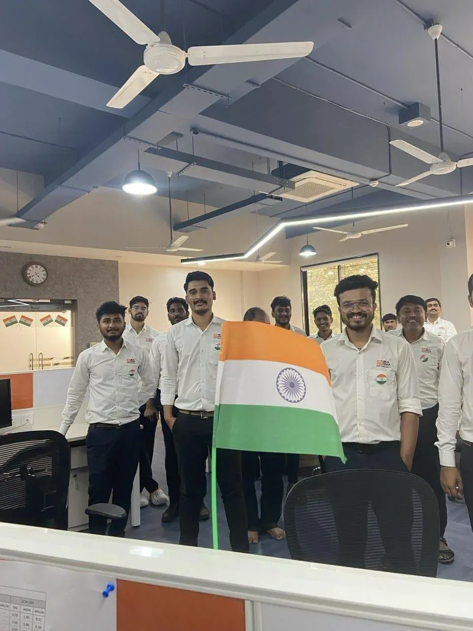 Engineers standing with the tricolour beside the flag pole inside the design office