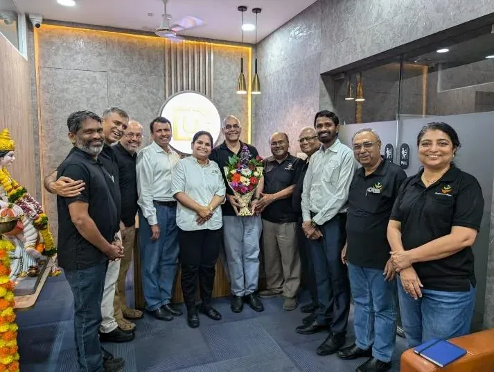 Urja-Disha leadership team with Bagwe Sir holding a bouquet in the reception, beside the illuminated company logo