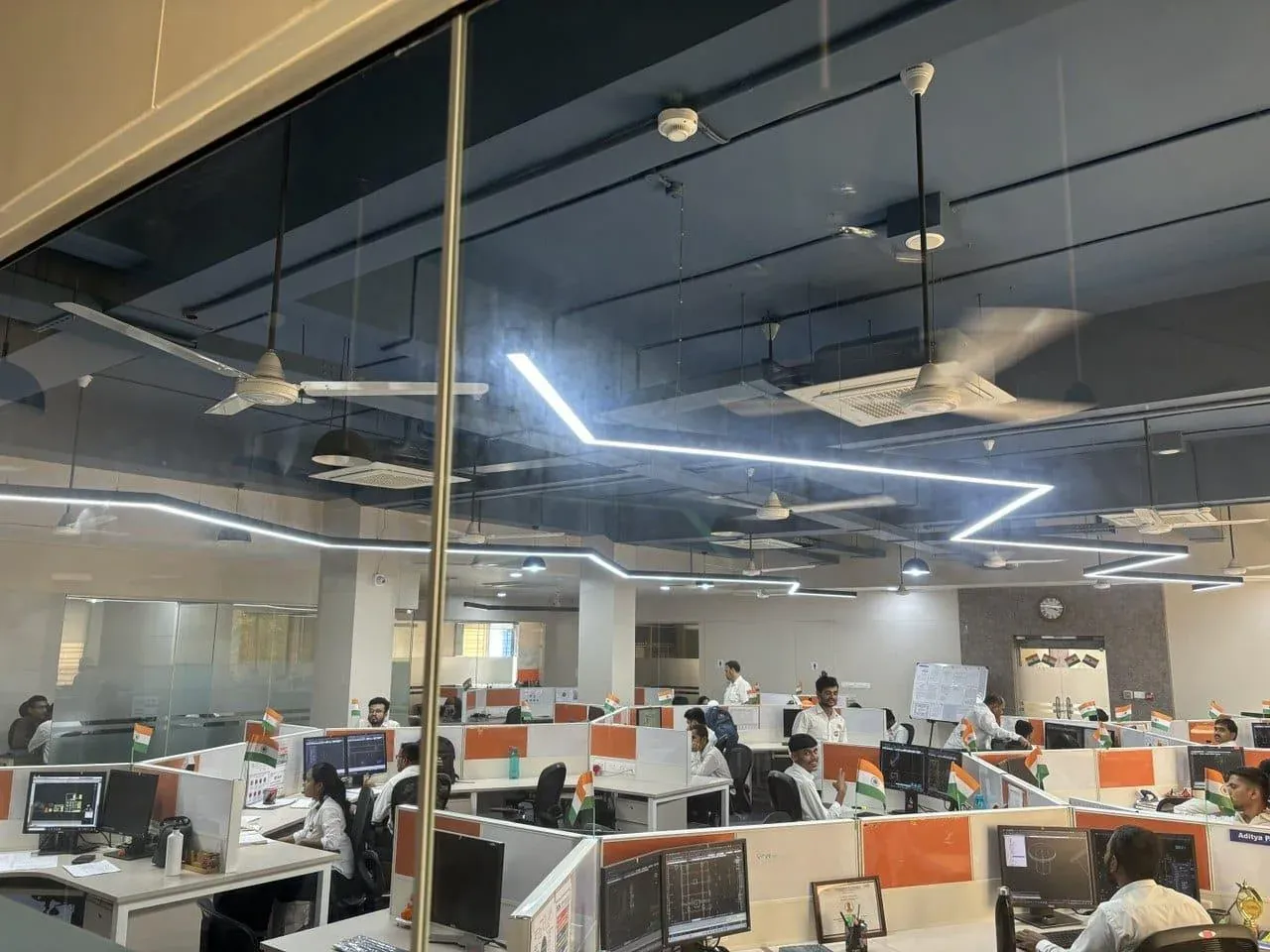 View through the glass wall of the engineering floor with small tricolour flags on every workstation