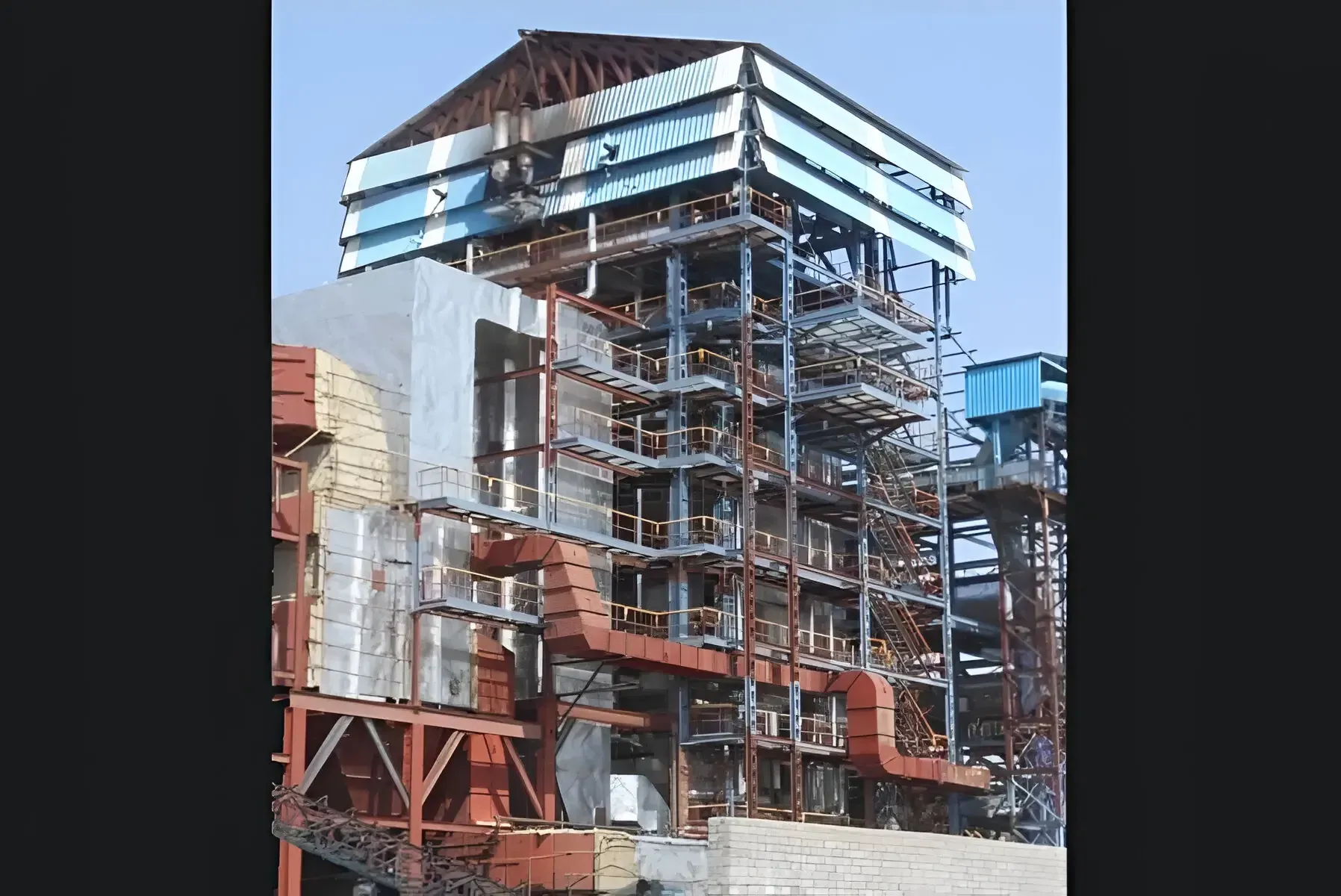 Tall multi-level fired boiler with ducting and access platforms at a plant site