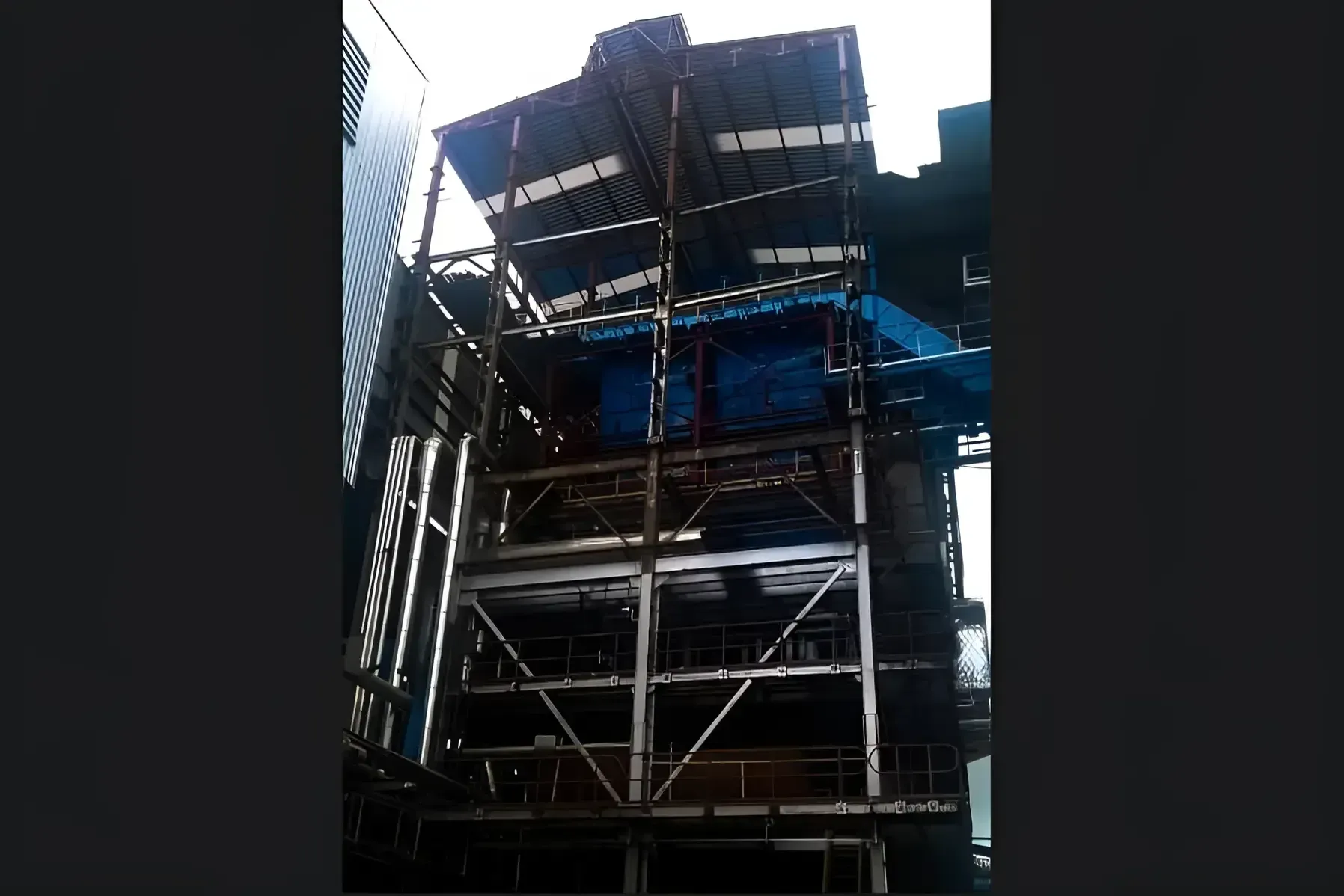 Retrofitted boiler seen from grade, new blue casing panels and steel structure with access platforms