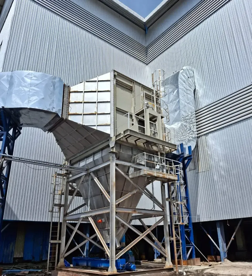 Rotary particulate collector with hopper, inlet and outlet ducting and access ladders erected outside a plant shed